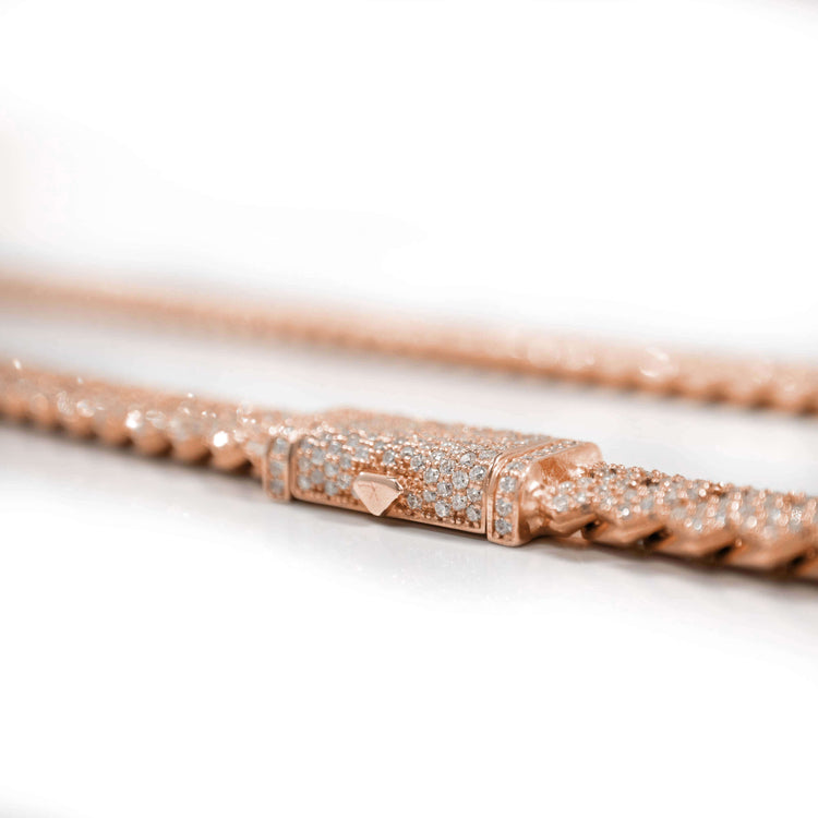 A close-up of the Diamond Cuban Link Chain – 8mm-17.5mm, crafted in solid 14k rose gold and featuring a diamond-encrusted clasp, displayed on a white background.