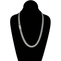 The Diamonds Cuban Link Chain (8mm-17.5mm) in solid white gold features a flat, interlocking silver design and a rectangular clasp with sparkling stones, elegantly displayed on a black velvet bust.