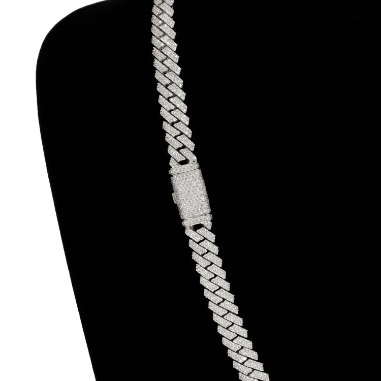 The Diamonds Cuban Link Chain - 8mm-17.5mm Solid White Gold is displayed diagonally on a black velvet stand, encrusted with small, sparkling natural diamonds.