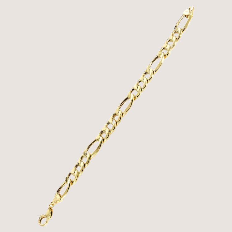 The Gold Figaro Bracelet - 6.5 mm features classic Italian design with alternating short and long links, crafted in radiant 14k gold, and is displayed diagonally on a plain light background.