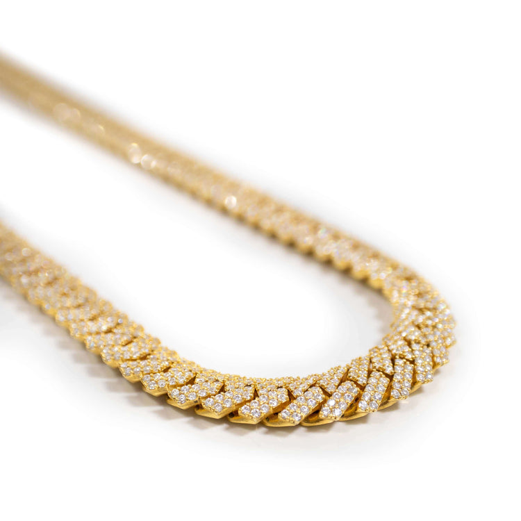 A close-up of a Moissanite Cuban Link Chain 8mm-23mm in solid yellow gold, featuring a herringbone design and encrusted with sparkling stones, displayed in a curved shape on a white background.