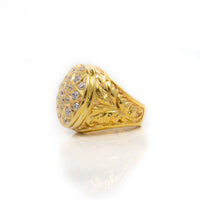 The Round Cluster Ring in Solid Gold features intricate engravings and a dome-shaped top adorned with round-cut stones, showcased on a white reflective surface.