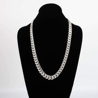 The Silver Cuban Link Chain - 14mm is shown on a black velvet bust with a plain white background. Its flat, tightly interlocking links give it a bold, polished appearance.