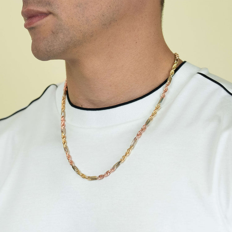 A man wears the Tricolor Milano Figarope - 4.5mm 14k Solid Gold chain, showcasing twisted gold, silver, and rose gold links that reflect fine Italian craftsmanship against a light yellow background.
