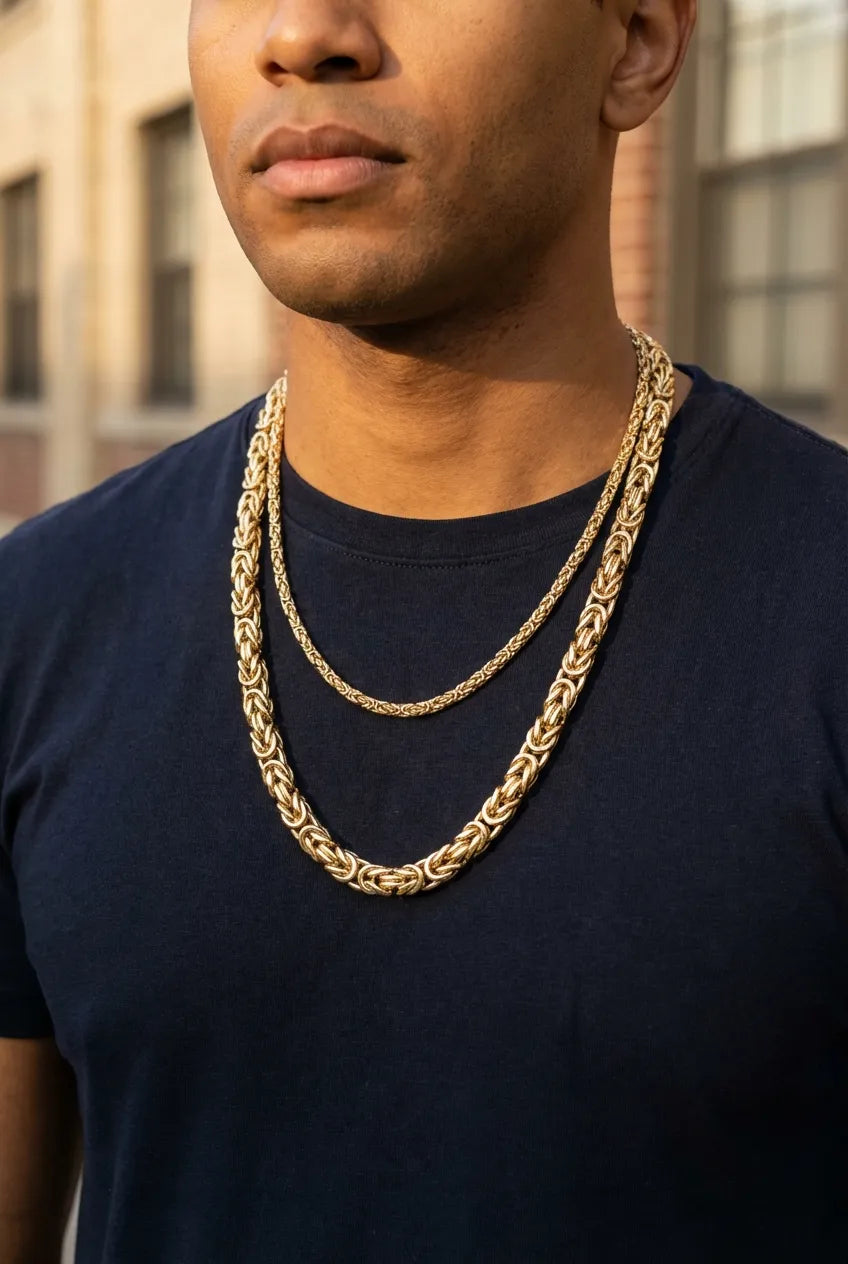 Man wearing a layered chain look with a Byzantine chain and Cuban link chain showing the textural contrast between chain styles