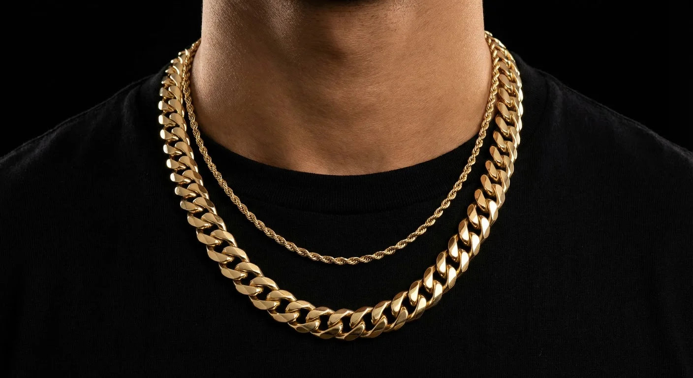 Close-up of a two-chain gold layering combo: thick 12mm Cuban link chain at 22 inches paired with a thin 3mm rope chain at 20 inches, warm gold tone against black background
