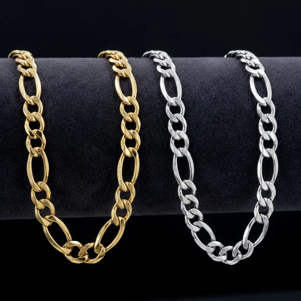 Yellow gold figaro chain and white gold figaro chain laid side by side showing identical 3+1 link pattern in warm gold tone versus cool silver tone, 8mm width