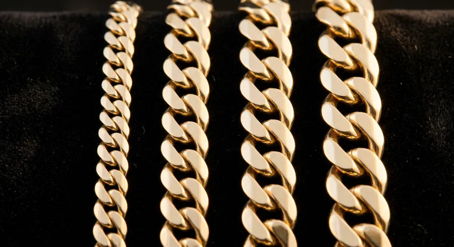 Close-up of handmade solid gold Cuban link chains in multiple widths from 7mm to 14mm displayed on black velvet