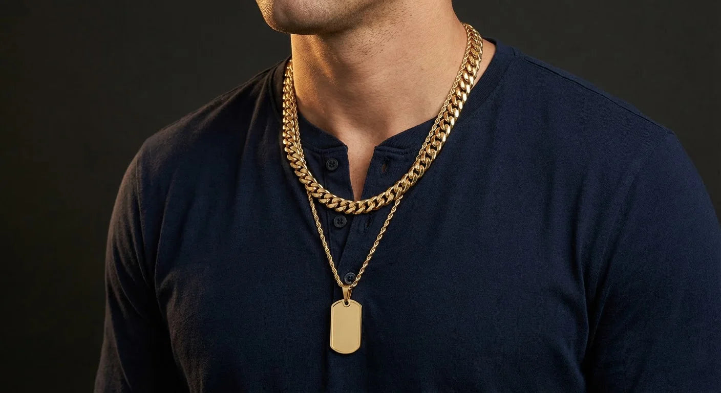 Man's chest wearing a thick gold Cuban link chain with a gold military dog tag pendant hanging at chest level, dark henley shirt, masculine jewelry styling