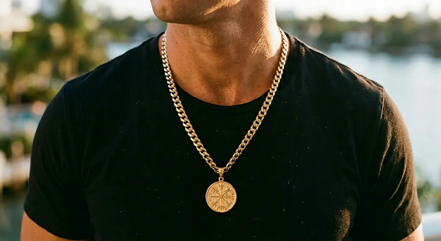 Man wearing a gold Vegvisir Viking pendant on a Cuban link chain over a black t-shirt, styled for modern streetwear