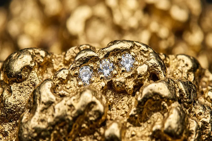 Close-up macro photograph of gold nugget jewelry texture showing organic ridges, crevices, and diamond detail